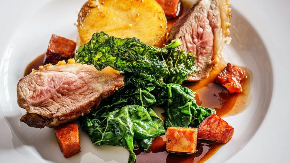 Savor a gourmet dish of roast lamb, crispy kale, and polenta, perfect for fine dining.